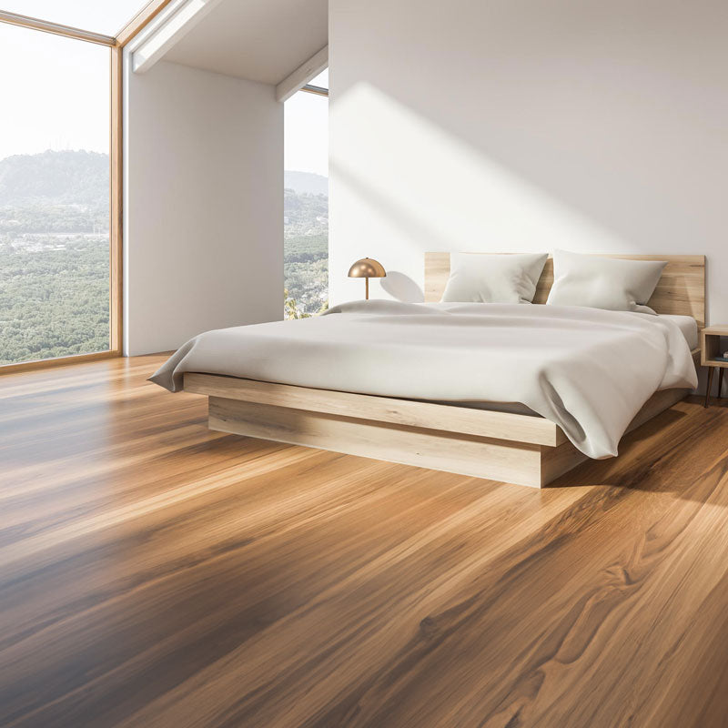 Sunlit bedroom with a low timber platform bed and floor-to-ceiling windows over wooded hills